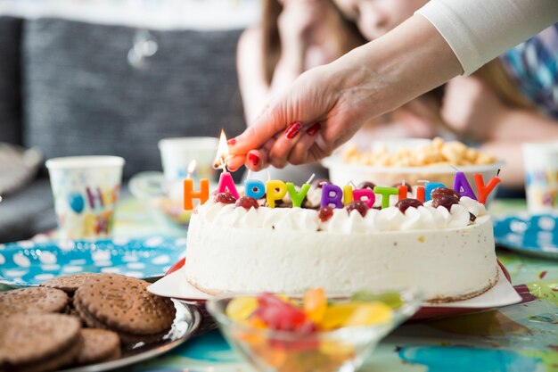 Mano de cultivo velas en llamas en la torta