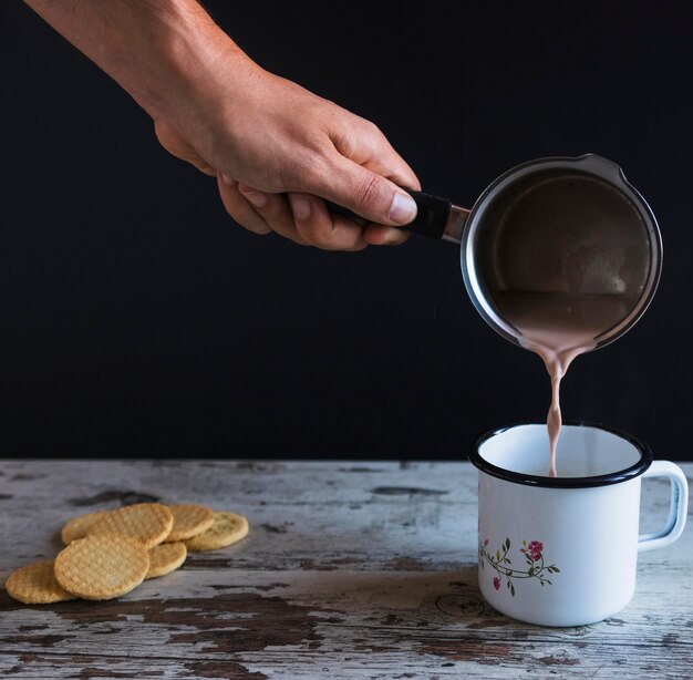 Mano de cultivo verter chocolate caliente en taza