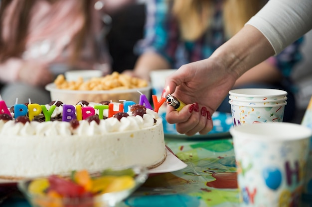 Mano de cultivos encender velas en la torta de cumpleaños