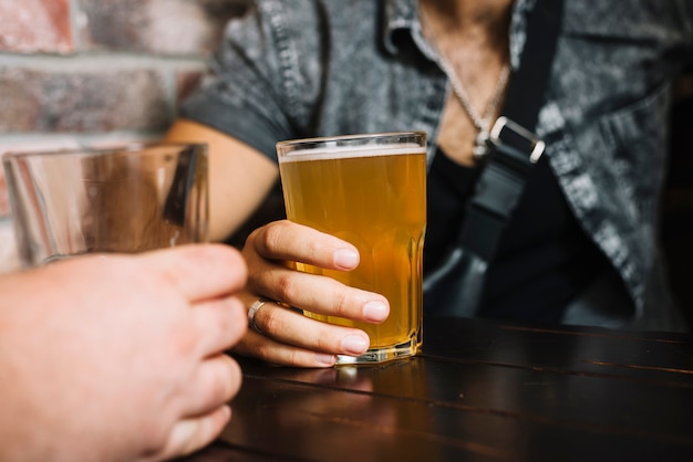 Mano de dos amigos sosteniendo un vaso de bebidas alcohólicas