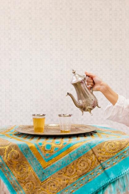 Foto gratuita mano echando té en vaso