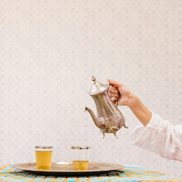 Mano echando té en vaso