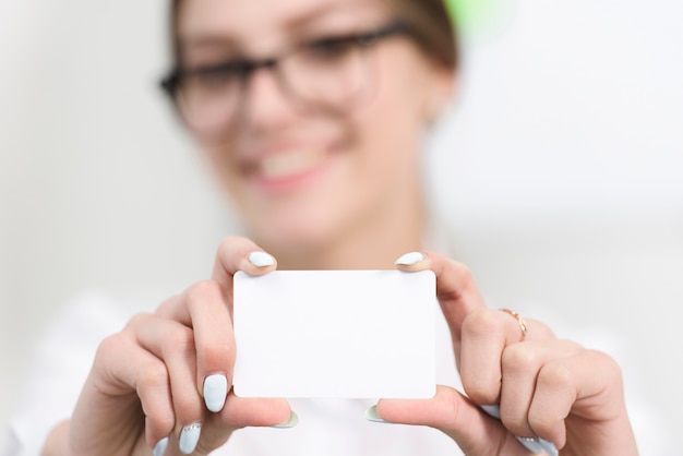 La mano de la empresaria que muestra la tarjeta de visita blanca en blanco hacia la cámara