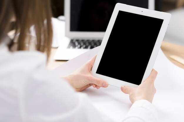 La mano de la empresaria que sostiene la tableta digital en la mano sobre el escritorio
