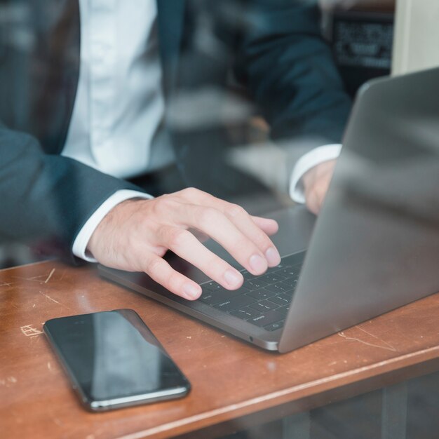 Mano del empresario escribiendo en la computadora portátil sobre el escritorio