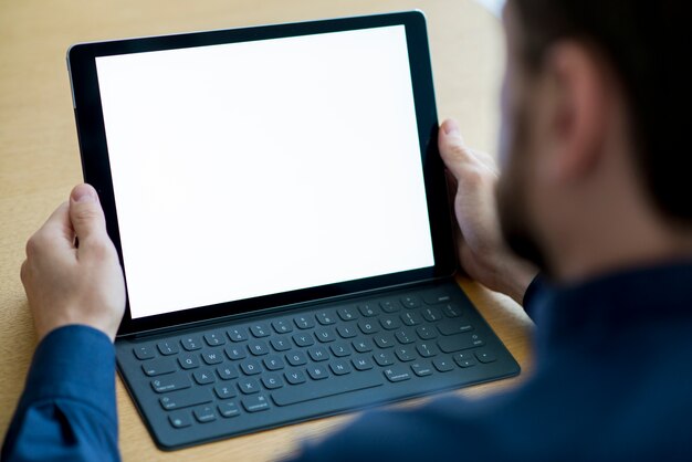 Mano del empresario que sostiene la tableta digital con pantalla blanca en blanco
