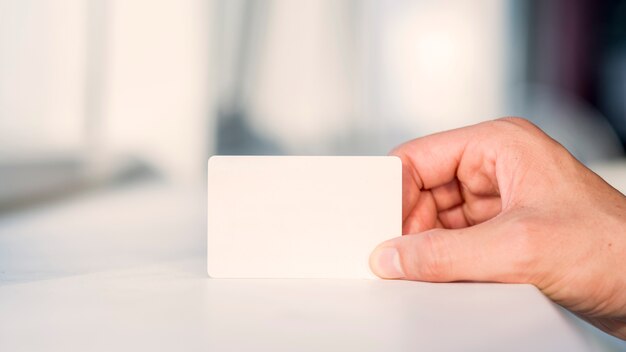 Mano del empresario que sostiene la tarjeta blanca en blanco