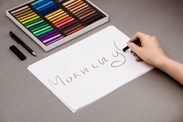 Foto gratuita mano escribiendo la palabra mañana en papel con lápices de colores pastel