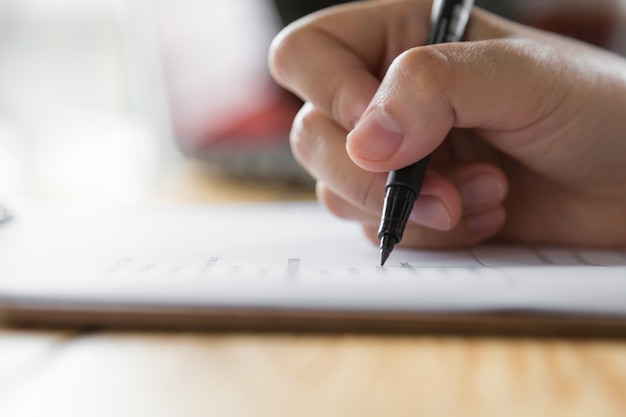 Mano escribiendo en un papel con un bolígrafo