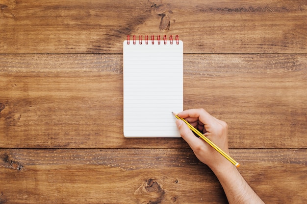 Mano escribiendo en una pequeña libreta