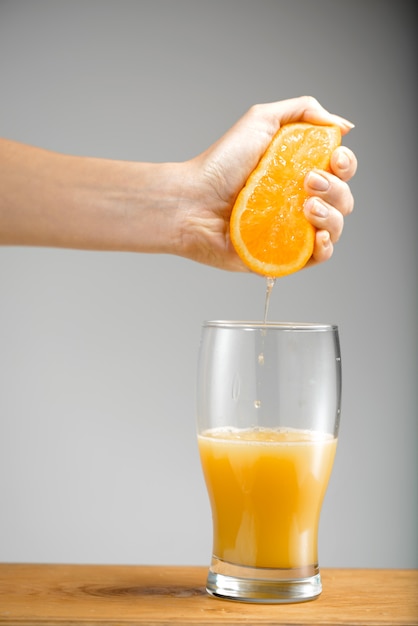 Foto gratuita mano exprimiendo el jugo de naranja en un vaso