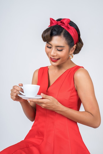 Mano feliz de la mujer de la moda que sostiene la taza de café