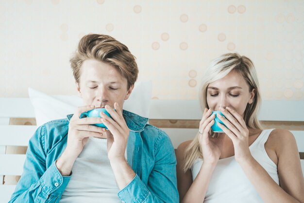 Mano feliz de los pares que sostiene la taza y que bebe el café por la mañana