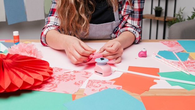 Foto gratuita mano femenina del artista que hace el molinillo de viento usando el papel del origami