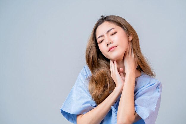 Mano femenina asiática enferma toca el cuello del cuerpo con mala sensación de dolor de garganta y estrés en el concepto de ideas de salud y enfermedad uniforme del hospital