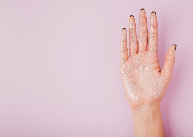 Foto gratuita mano femenina con brillo y copia espacio fondo rosa