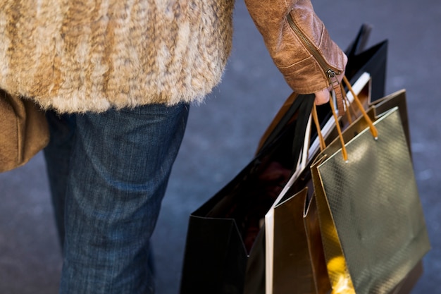 Mano femenina de la cosecha que sostiene bolsos de compras