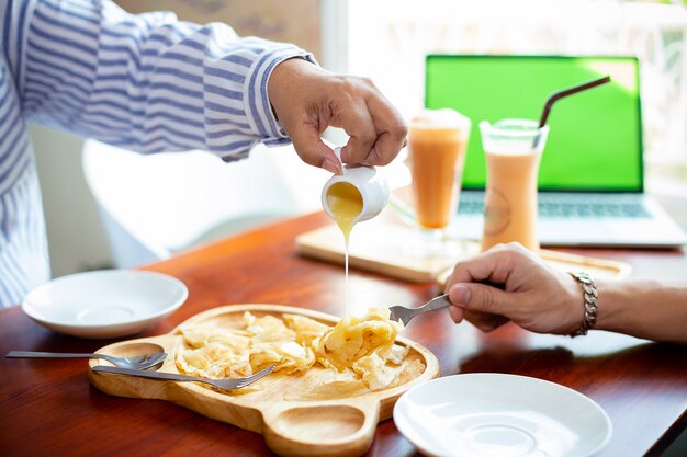 Mano femenina está vertiendo leche sobre pasteles crujientes roti