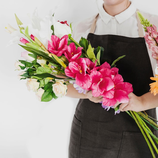 Mano femenina de la florista que sostiene el manojo de flores blancas y rojas