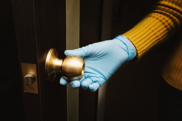 Mano femenina en guante protector abre una puerta