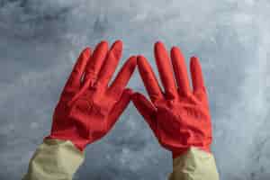 Foto gratuita mano femenina en guantes protectores rojos sobre mármol.