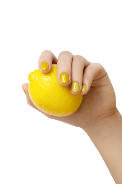 Mano femenina con manicura glitter con limón