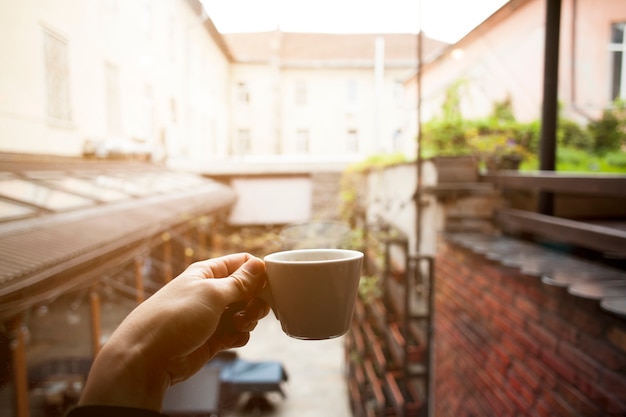 Mano femenina del primer que sostiene la taza de café caliente