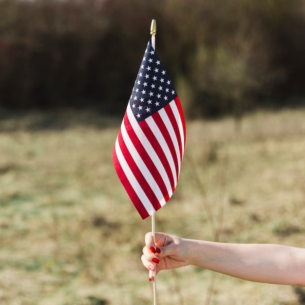 Mano femenina que sostiene la bandera de Estados Unidos durante el día de la independencia