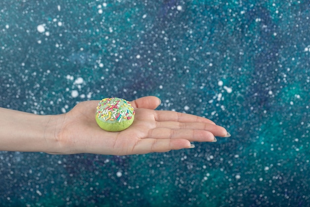 Foto gratuita mano femenina que sostiene la galleta verde con chispitas.