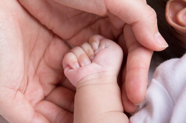 Mano femenina que sostiene la mano del bebé recién nacido