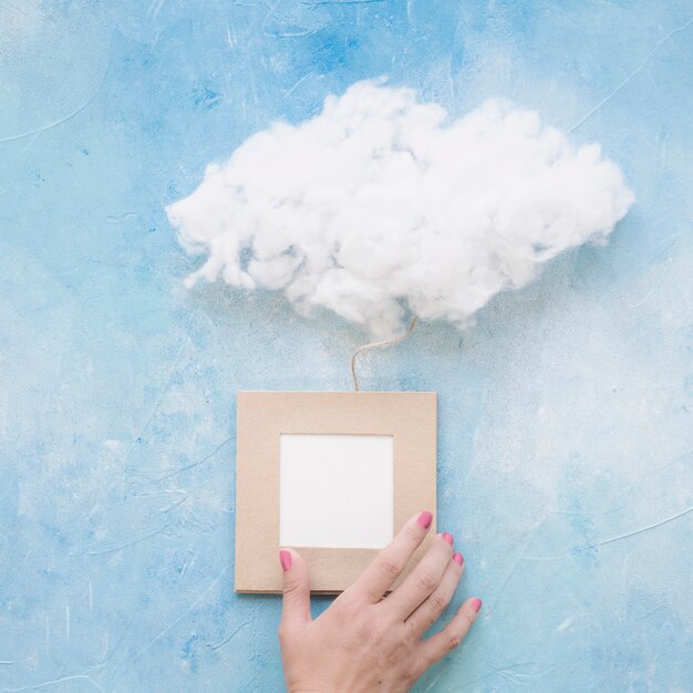 Mano femenina que sostiene el marco con la nube