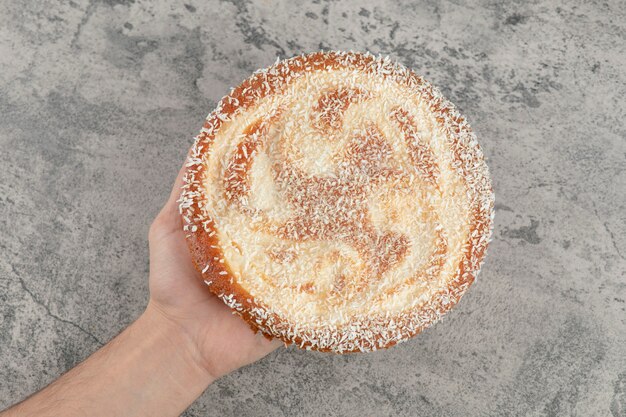 Foto gratuita mano femenina que sostiene la tarta de manzana dulce en la superficie de mármol.