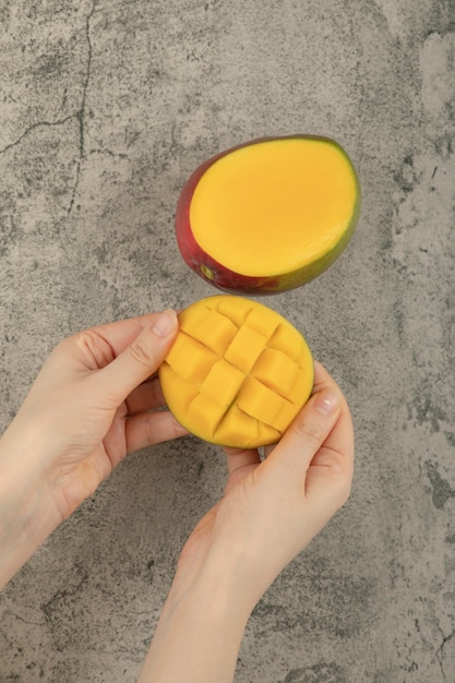 Foto gratuita mano femenina rompiendo frutos de mango exóticos en la superficie de mármol