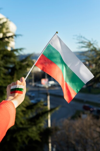 Mano femenina sosteniendo la bandera de tela de bulgaria