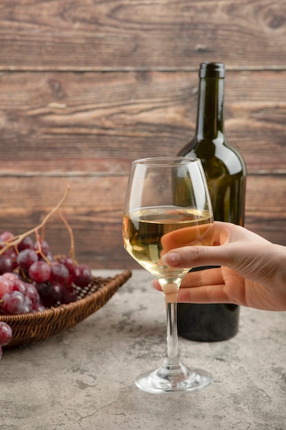 Foto gratuita mano femenina sosteniendo una copa de vino blanco sobre la mesa de mármol.