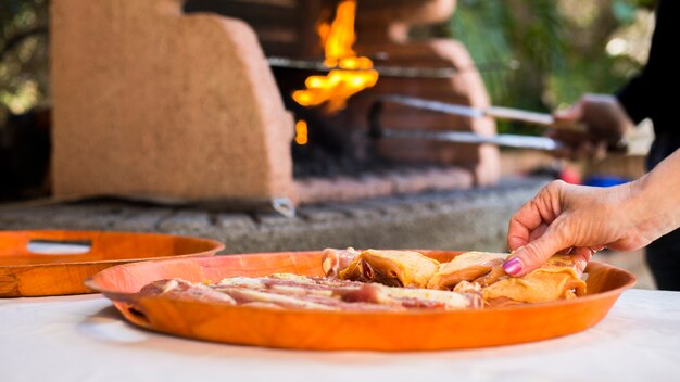 Mano femenina sosteniendo pollo crudo para asar a la parrilla