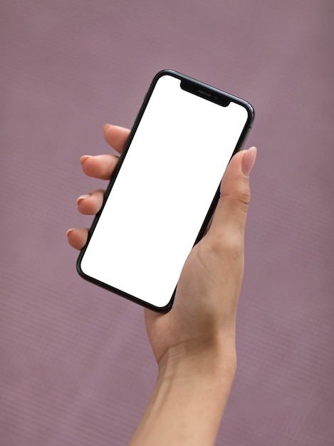Mano femenina sosteniendo un teléfono inteligente con pantalla en blanco