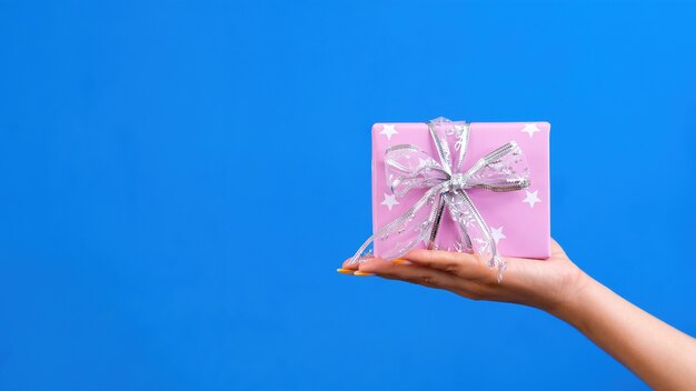 Mano femenina sostiene una caja de regalo