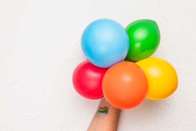 Mano con globos en colores LGBT.