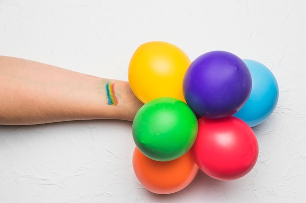 Mano con globos y rayas en colores LGBT.