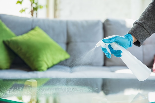 Mano en guantes desinfectando superficies con desinfectante en casa