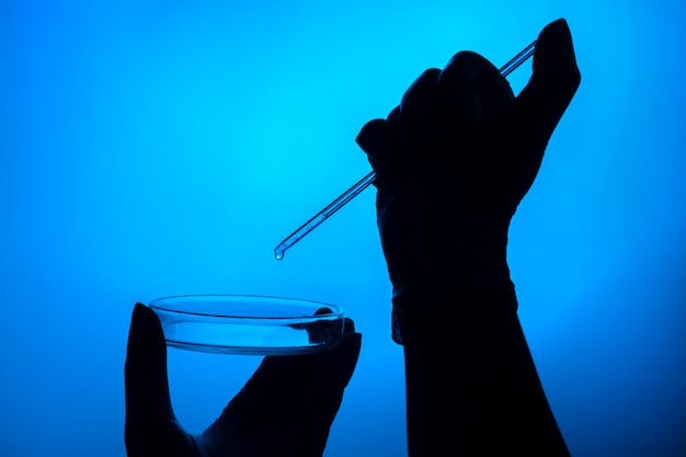 Mano haciendo una prueba en laboratorio con placa de Petri y gotero