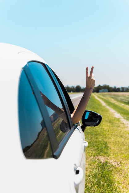 Mano haciendo el signo de la paz a través de la ventana del coche