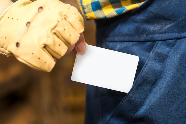 Mano de Handyman sacando la tarjeta de visita blanca del bolsillo.