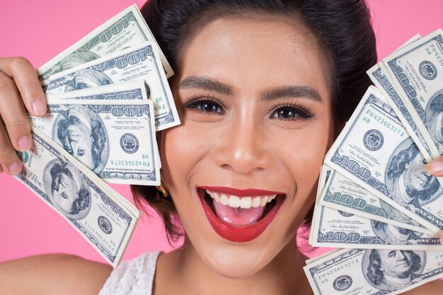 Mano hermosa de la mujer de la moda feliz que sostiene el dinero del dólar