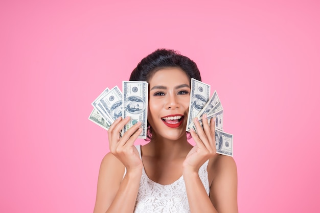 Mano hermosa de la mujer de la moda feliz que sostiene el dinero del dólar