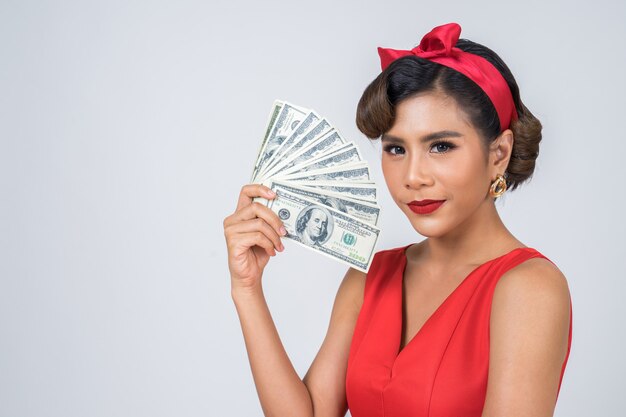 Mano hermosa de la mujer de la moda feliz que sostiene el dinero del dólar