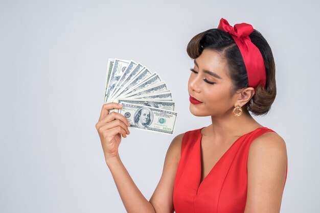 Mano hermosa de la mujer de la moda feliz que sostiene el dinero del dólar