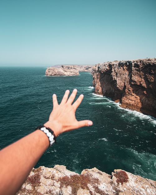 Foto gratuita mano de un hombre hacia los acantilados y el mar