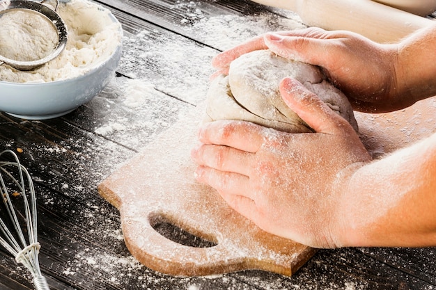 La mano del hombre amasando la harina con harina de trigo